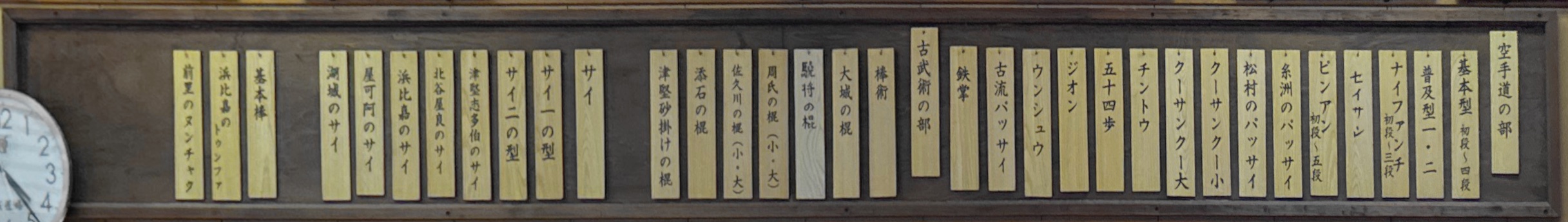 Wooden nafuda on the wall of Sensei Tsuha’s dōjō, listing the Shōrin-ryū kata and kobudō from right to left.